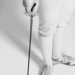 Fencer holding a foil sword pointed towards the ground