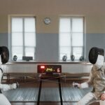 Two foil fencers fencing with electric equipment